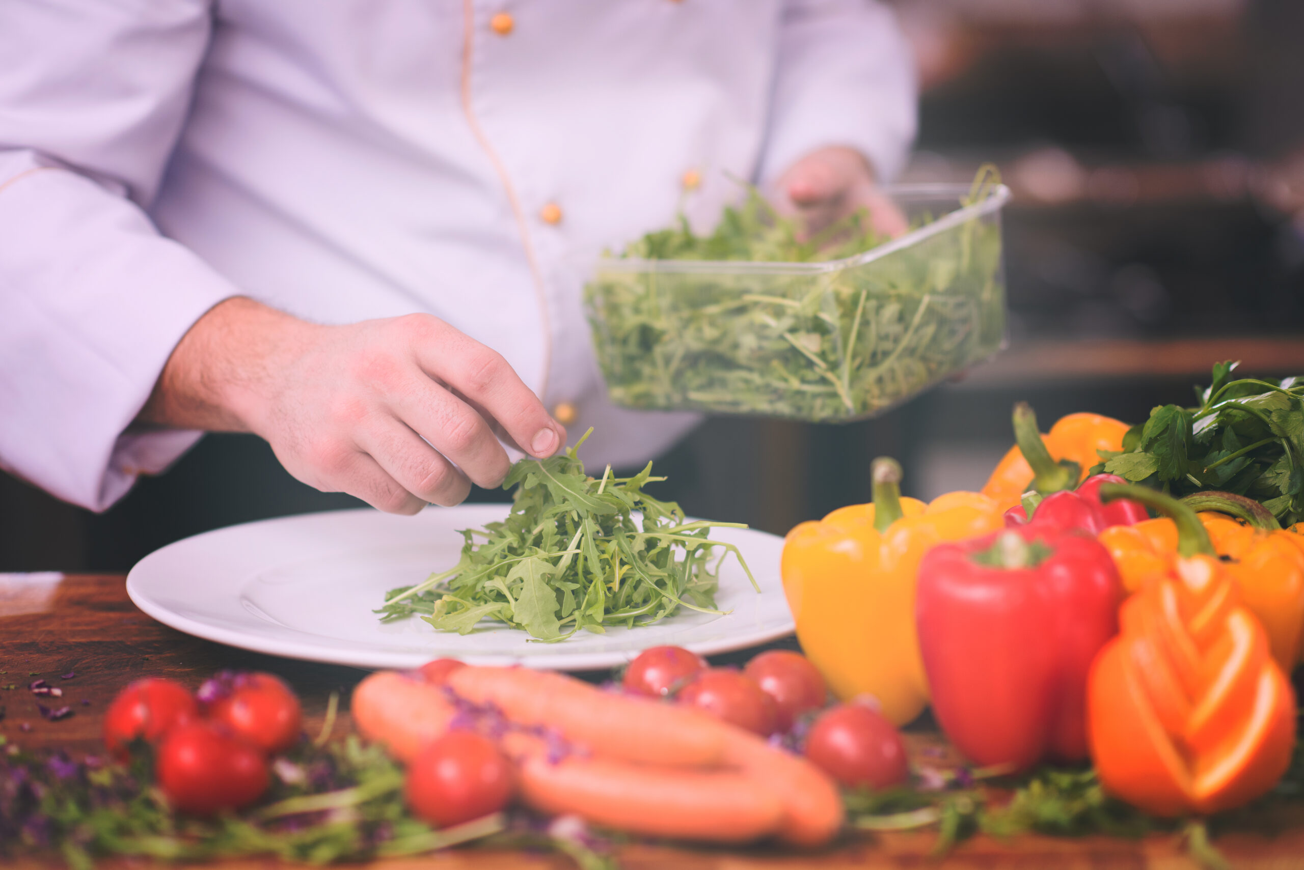 chef serving vegetable salad on plate in restaurant kitchen